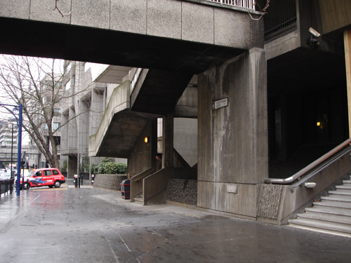 Overhead, the public walkway descends to street level.