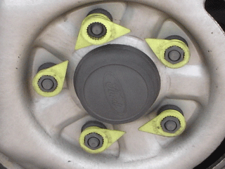 Close up of wheel nuts with yellow plastic torque checkers